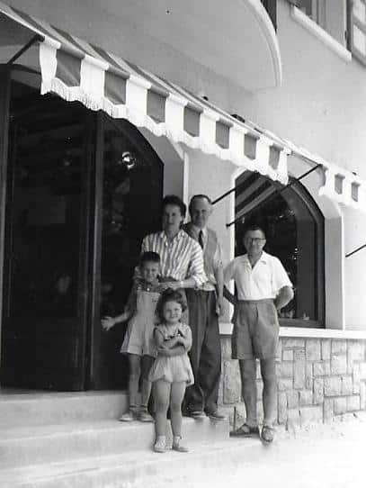 Anchierri, sa femme et son fils avec un ami et sa fille sur les marches de la boutique, août 1954